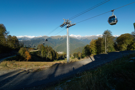 Cableway among the mountains with green slopes and snowy peaksの写真素材