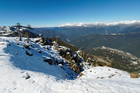 Panoramic view from the top of the Aibga mountain range to the ski resort with cableway. The valley is surrounded by high mountains with snowy slopes. Krasnaya Polyana, Sochi, Caucasus, Russia.の写真素材