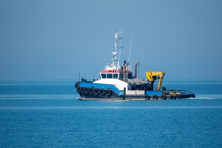 The sea tug comes out of the harbor. Sea harbor on a sunny day.の写真素材