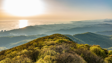 Layers of mountains and the sea in a haze in the light of the sunshine. Green valley with the city Sochi in the sunshine. View from Mount Akhun, Sochi, Russia.の写真素材
