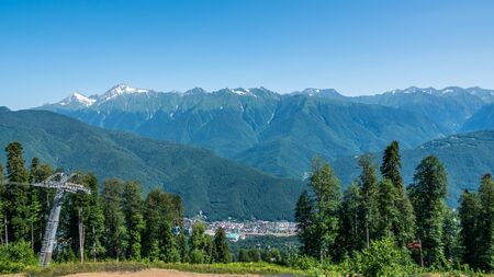 A panoramic view of the Valley with apartment buildings, surrounded by mountains with cable cars. Krasnaya Polyana, Sochi, Caucasus, Russia.の写真素材