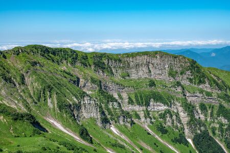 Mountain range with rocks and trees against a clear blue sky. Mountain peak in the summer.の写真素材