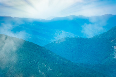 Layers of green mountains and hills in the haze and fog. Krasnaya Polyana, Sochi, Caucasus, Russia.