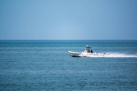 A coast guard patrol boat sails near the shore on a clear sunny day.の写真素材