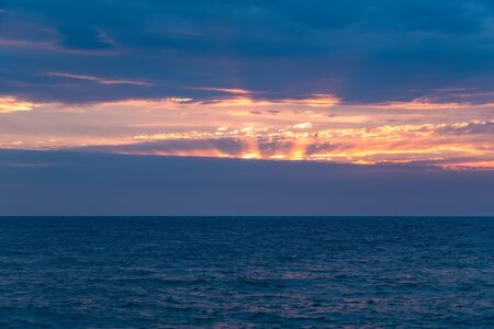 Beautiful orange sunset over the sea in a cloudy sky.の写真素材