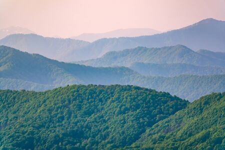 Layers of green mountains and hills in the haze during sunset. Beautiful sunset in the hills and mountains. Beautiful sunset in a hilly valley with fog in the lowlands.の写真素材