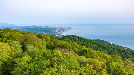 Green sea shore with residential buildings in the sunset light. View from Mount Akhun, Sochi, Russia.の写真素材