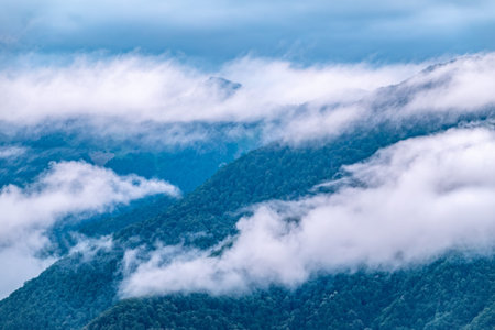 High mountain with green slopes hidden in thick clouds and fog. Heavy fog in the mountains on a...
