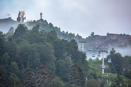Green mountain slope with cable cars and ski runs at overcast summer sunset. Black Pyramid Mountain, Krasnaya Polyana, Sochi, Caucasus, Russiaの写真素材