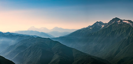 High mountains with green slopes and snowy peaks. Mountain ranges in summer. Layers of mountains in...