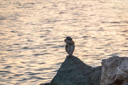 Balancing stones in equilibrium. Meditation and relaxation on the beach at sunset.の写真素材