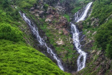 Green mountain range with waterfall and in spring or summer. Powerful stream of mountain river with waterfall. Achipsa waterfalls, Krasnaya Polyana, Sochi, Russiaの写真素材
