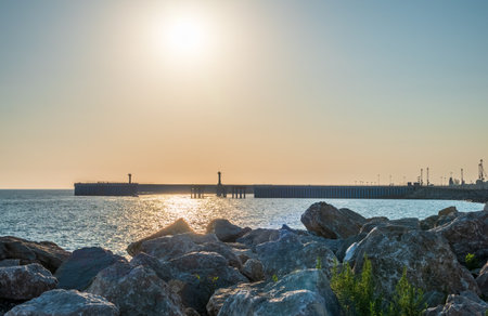 Large stones and rocks against the background of the seaport. Breakwater of large stones on the sea...