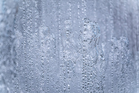 Splashes of water against light background. Fountain, a jet of water against cloudy sky.