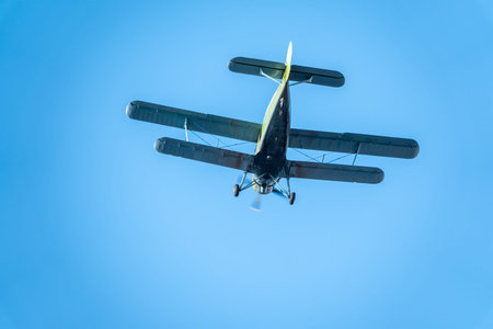 Retro green biplane plane in the blue sky. Old airplane against blue sky