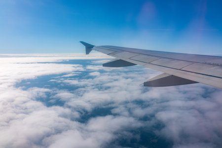 View from the airplane window at a beautiful cloudy sky and the airplane wing. Earth and sky as seen through window of an airplane.の写真素材