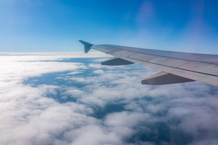 View from the airplane window at a beautiful cloudy sky and the airplane wing. Earth and sky as seen through window of an airplane.の写真素材