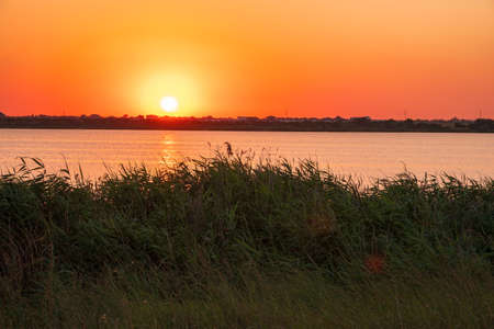 The sun goes down over a lake. Dramatic Sunset Skyの写真素材