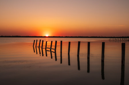 Beautiful red and orange sunset over the sea. The sun goes down over the sea. An old sea pier in orange sunset light. Dramatic Sunset Skyの写真素材