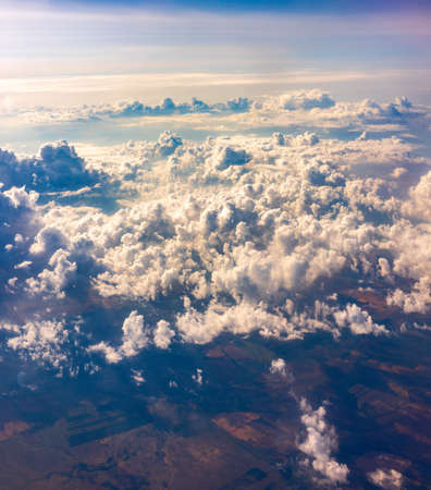 Aerial view from airplane window above green ground. View from the airplane window with beautiful clouds at sunrise. Earth and sky as seen through window of an airplane.の写真素材