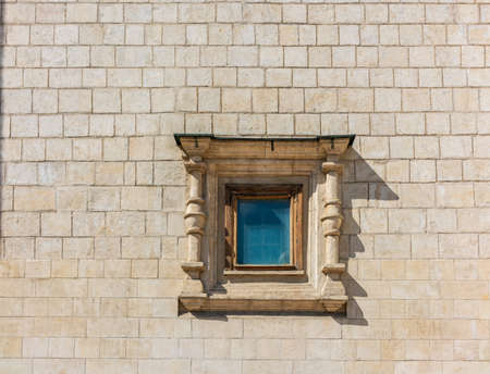 Small window in an ancient medieval wall. White Stone Castle Wall with Small Windowの写真素材