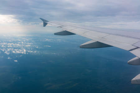 View from the airplane window at a beautiful blue sunrise and the airplane wing in clear sky. Earth and sky as seen through window of an airplane.の写真素材