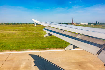 View of airplane wing, blue skies and green land with plane shadow during landing. Airplane window view. Earth and sky as seen through window of an airplane.の写真素材