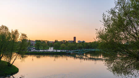 A pond in the Tsaritsino city park on a summer evening with people on bridge. A summer landscape on a pond in the warm summer evening. Moscow, Russiaの写真素材