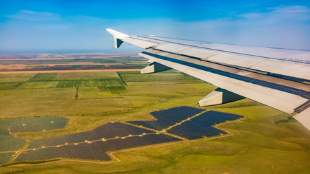 View of airplane wing, blue skies and green land during landing. Airplane window view. Earth and sky as seen through window of an airplane.の写真素材