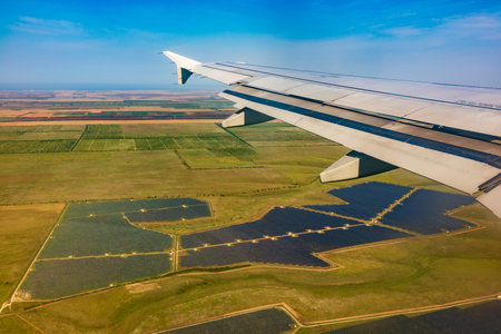 View of airplane wing, blue skies and green land during landing. Airplane window view. Earth and sky as seen through window of an airplane.の写真素材