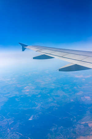 View from the airplane window at a beautiful clear blue sky and the airplane wing. Earth and sky as seen through window of an airplane.の写真素材
