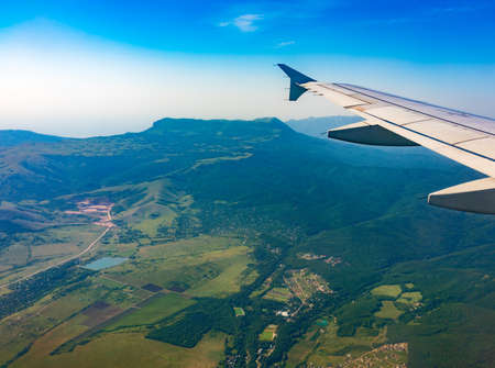 View of airplane wing, blue skies and green land during landing. Airplane window view. Earth and sky as seen through window of an airplane.の写真素材