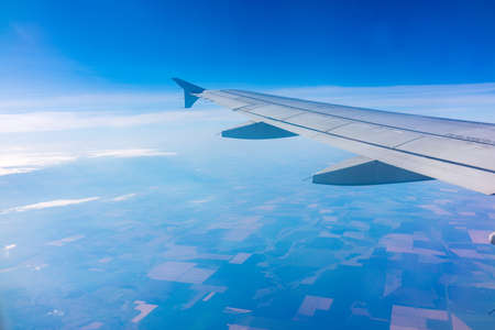 View from the airplane window at a beautiful clear blue sky and the airplane wing. Earth and sky as seen through window of an airplane.の写真素材