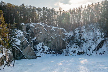 Sheer cliffs and rocks around the Talc quarry in winter in Russia in the town of Sysert, near Yekaterinburg. Pine and birch on a snow-covered rockの写真素材