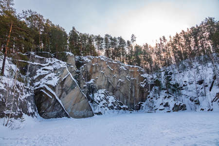 Sheer cliffs and rocks around the Talc quarry in winter in Russia in the town of Sysert, near Yekaterinburg. Pine and birch on a snow-covered rockの写真素材