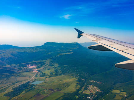 View of airplane wing, blue skies and green land during landing. Airplane window view. Earth and sky as seen through window of an airplane.の写真素材