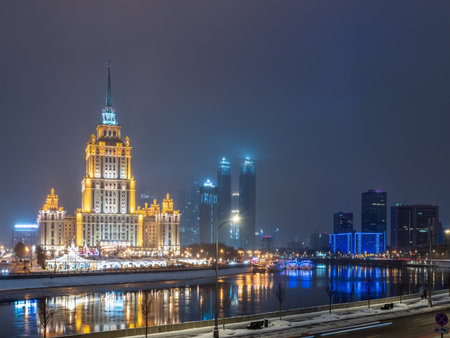Illuminated high-rise stalinist building near river at winter night in Moscow, Russia. Winter urban cityscape. Translation of the Inscription on the facade - Ukraine.の写真素材