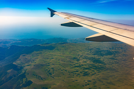 View of airplane wing, blue skies and green land during landing. Airplane window view. Earth and sky as seen through window of an airplane.の写真素材