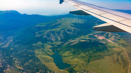 View of airplane wing, blue skies and green land during landing. Airplane window view. Earth and sky as seen through window of an airplane.の写真素材