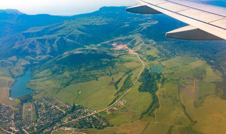 View of airplane wing, blue skies and green land during landing. Airplane window view. Earth and sky as seen through window of an airplane.の写真素材