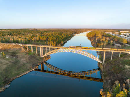 Beautiful view of the arched railway bridge across the Iset River in the city of Kamenkk-Uralsky at sunset in spring. Kamensk-Uralskiy, Sverdlovsk region, Ural mountains, Russia. Aerial viewの写真素材