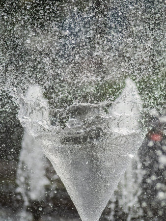 Water splashes from fountain on dark background. Natural texture of only water of fountain. High waves effect in hot summer with copy space. Water sprays in sunny day close-up.の写真素材