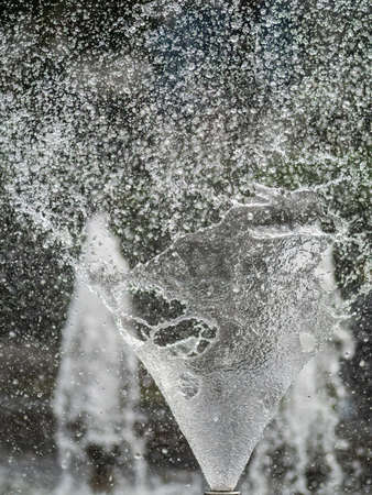 Water splashes from fountain on dark background. Natural texture of only water of fountain. High waves effect in hot summer with copy space. Water sprays in sunny day close-up.の写真素材
