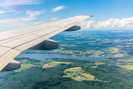 View of airplane wing, blue skies and green land during landing. Airplane window view. Earth and sky...