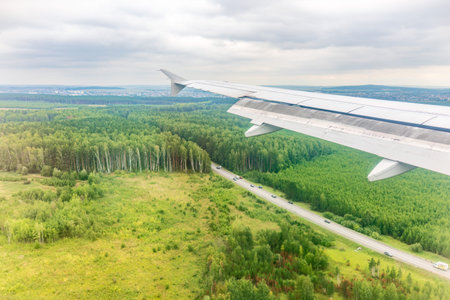 View of airplane wing, blue skies and green land during landing. Airplane window view. Earth and sky as seen through window of an airplane.の写真素材