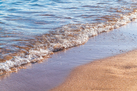 Soft wave of the sea on the sandy beach. Sea wave and gold sand.