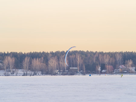Kite surfer ride on snowboard. Snowkiting in the snow on frozen lake. Kiteboarding in winterの写真素材
