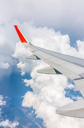 View from the airplane window at a beautiful cloudy sky and the airplane wing. Earth and sky as seen...