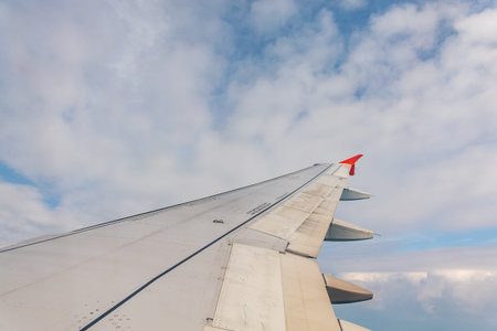 View from the airplane window at a beautiful cloudy sky and the airplane wing. Earth and sky as seen...