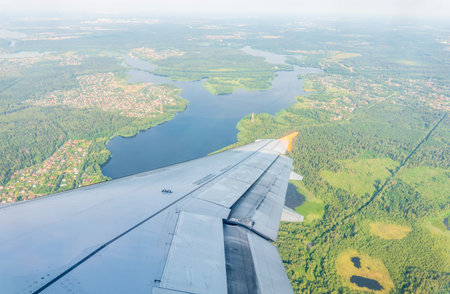 View of airplane wing, blue skies and green land during landing. Airplane window view. Earth and sky...